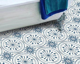 May include: Blue and white patterned tile flooring with a vintage design. The tiles feature a circular motif with floral accents. A white bathtub with a blue towel is in the background.