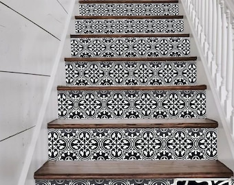 May include: Staircase with decorative black and white tile stickers applied to the risers. The stickers feature a repeating floral pattern. The stairs have wooden treads and are set against a white wall and banister.