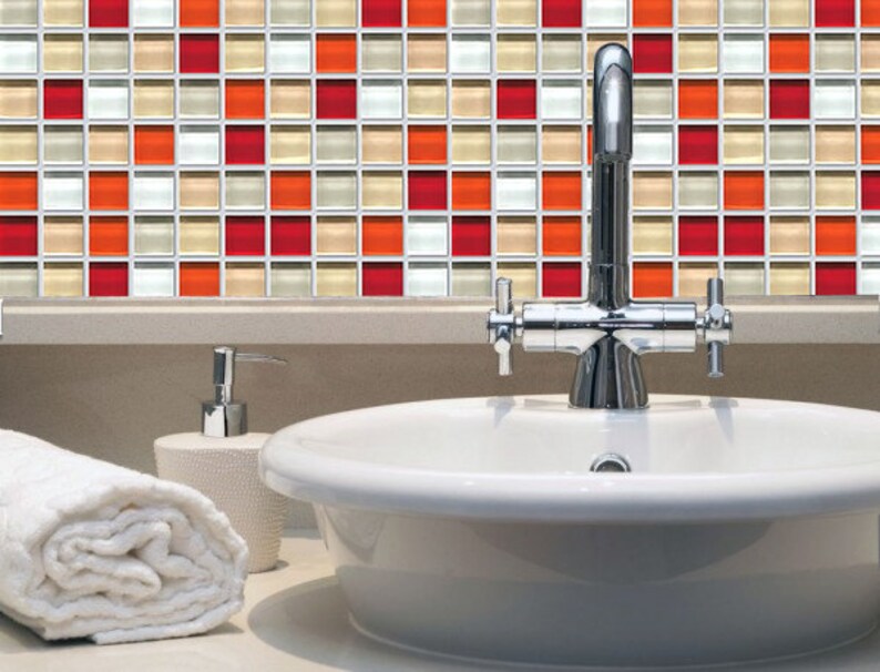 May include: A bathroom interior with a white sink, chrome tap, and a decorative tile backsplash. The mosaic tile features red, orange, beige, and white squares. A rolled white towel and soap dispenser are also present.