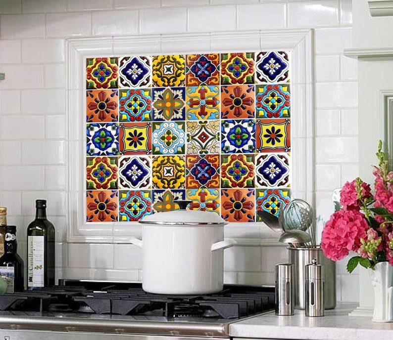Puede incluir: Una escena de cocina con una olla blanca sobre una estufa y un colorido protector contra salpicaduras de azulejos enmarcado por una ventana blanca. Los azulejos muestran intrincados dise&ntilde;os florales en varios colores, incluyendo azul, amarillo y naranja. Decoraci&oacute;n de cocina.