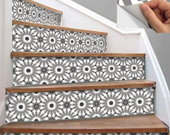 May include: Staircase with decorative gray and white patterned stair risers. The risers feature a repeating geometric starburst design. The stairs have wooden treads and white painted stringers. A hand is peeling a sticker with the same pattern.