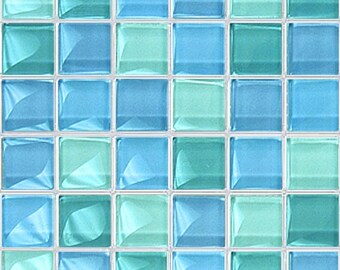 May include: A mosaic tile sheet with a grid of square tiles in shades of blue and teal. The tiles have a glossy, reflective surface, creating a shimmering effect. The tiles are arranged in a repeating pattern.