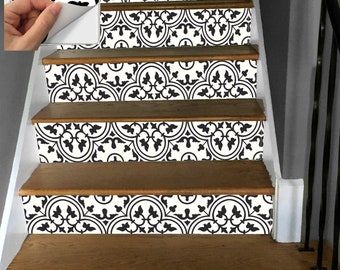May include: Staircase with decorative black and white tile stickers applied to the risers. The stickers feature a repeating geometric pattern. The stairs have wooden treads and white painted risers. A hand is peeling a sticker from its backing in the corner.