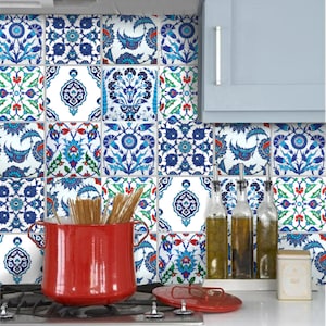 Puede incluir: Un salpicadero de cocina con azulejos cuadrados con intrincados diseños florales azules y blancos. Una olla roja está sobre la estufa y se ven botellas de aceite de oliva. Los azulejos añaden un toque decorativo.