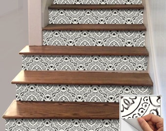 May include: Staircase with decorative black and white patterned tile risers. The risers feature a repeating circular design. The wooden steps are a warm brown color. A sample tile with a peeling corner is shown in the lower right corner.