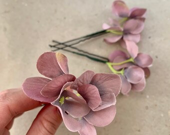 May include: Two sets of hair clips with mauve fabric flowers. Each set has three flowers and a silver bobby pin.