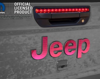 May include: A close-up of a Jeep tailgate with a red third brake light and a pink Jeep logo. The text "MOPAR. OFFICIAL LICENSED PRODUCT" is visible on the tailgate.