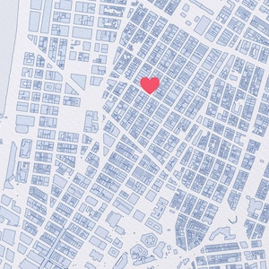 Może przedstawiać: Szczegółowa ilustracja mapy w odcieniach niebieskiego, z czerwonym symbolem serca. Mapa przedstawia układ miasta z ulicami i budynkami, sugerując planowanie urbanistyczne. Serce jest centralnie umieszczone.
