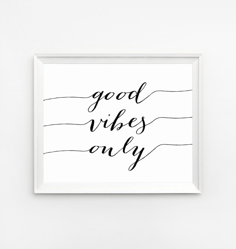 May include: A framed print with the words "good vibes only" in elegant black script. The text is centered on a white background, with three horizontal lines. The frame is white.