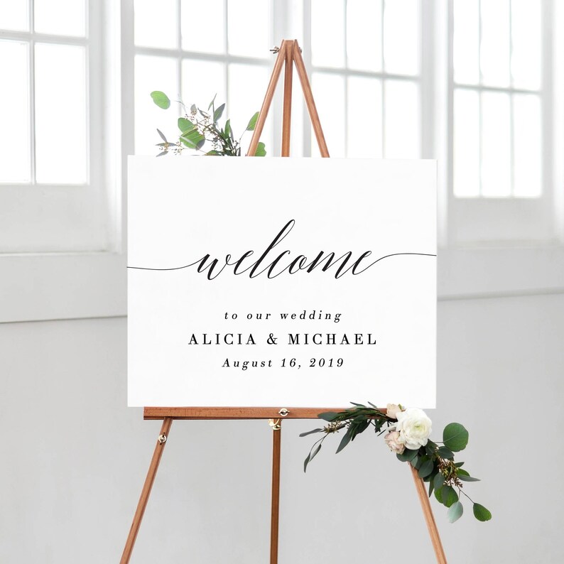 May include: A white welcome sign with black calligraphy that reads "welcome" to our wedding Alicia & Michael August 16, 2019. The sign is on an easel.