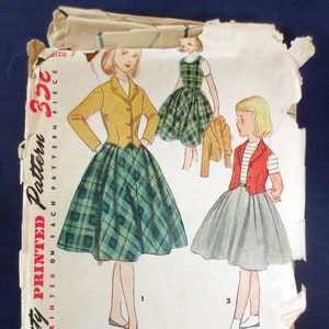 May include: Vintage Simplicity printed pattern featuring illustrations of women's and girls' clothing designs. The designs include a plaid skirt and jacket, a plaid dress, and a gray skirt with a red vest. The pattern details are printed on the front.