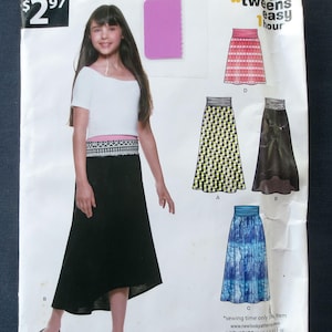 May include: A white ceramic mug with a black handle and the text "But First, Coffee" in a bold, black font. The mug is set against a blurred background, suggesting a cozy setting.