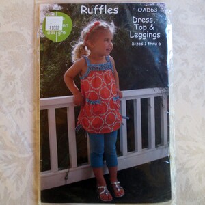 May include: A sewing pattern for a dress, top and leggings. The pattern is called "Ruffles" and is from "Ann Designs". The pattern is for sizes 1 through 6.