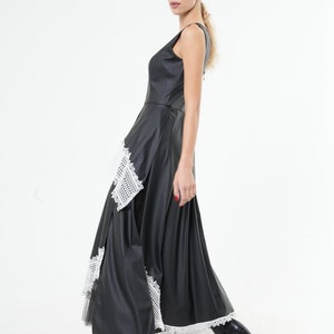 May include: A black maxi dress with a white lace trim. The dress has a sleeveless design and a fitted bodice. The skirt is flowing and has a layered look.