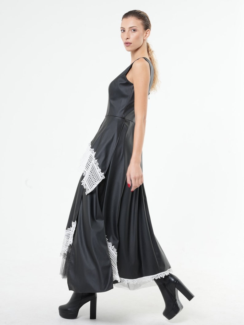 May include: A black maxi dress with a white lace trim. The dress has a sleeveless design and a fitted bodice. The skirt is flowing and has a layered look.