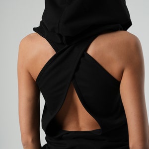 May include: Black hooded tank top with a criss-cross back design. The top has a large hood that can be worn up or down.
