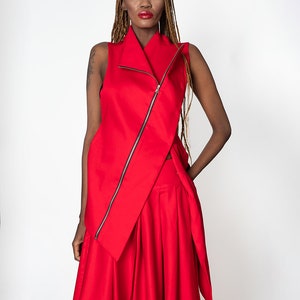 May include: A red sleeveless top with a long zipper down the front and a long red skirt. The top has a high collar and the skirt has a flowing design.