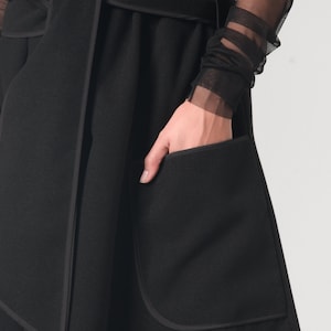 May include: A black long-sleeved wrap coat with a self-tie belt and a large patch pocket on the front.