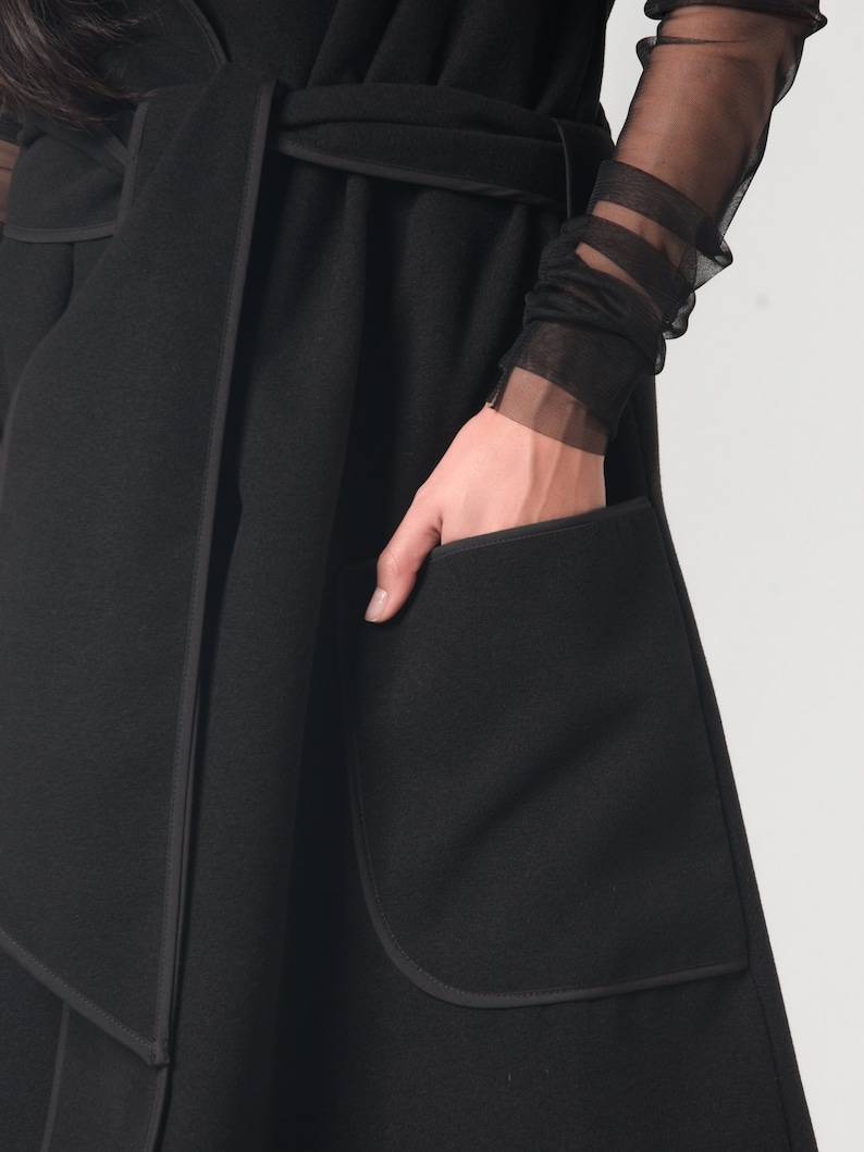 May include: A black long-sleeved wrap coat with a self-tie belt and a large patch pocket on the front.