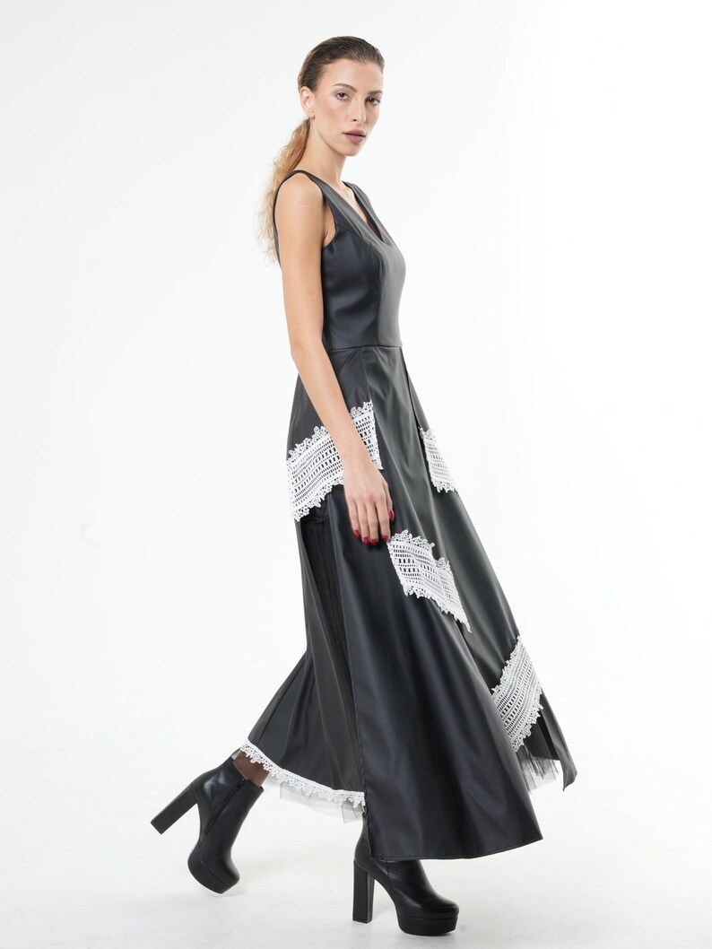 May include: A black maxi dress with a V-neckline and white lace trim. The dress has a fitted bodice and a flowing skirt.