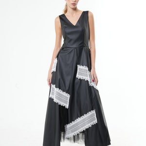May include: A black maxi dress with a V-neckline and white lace detailing. The dress has a fitted bodice and a flowing skirt.