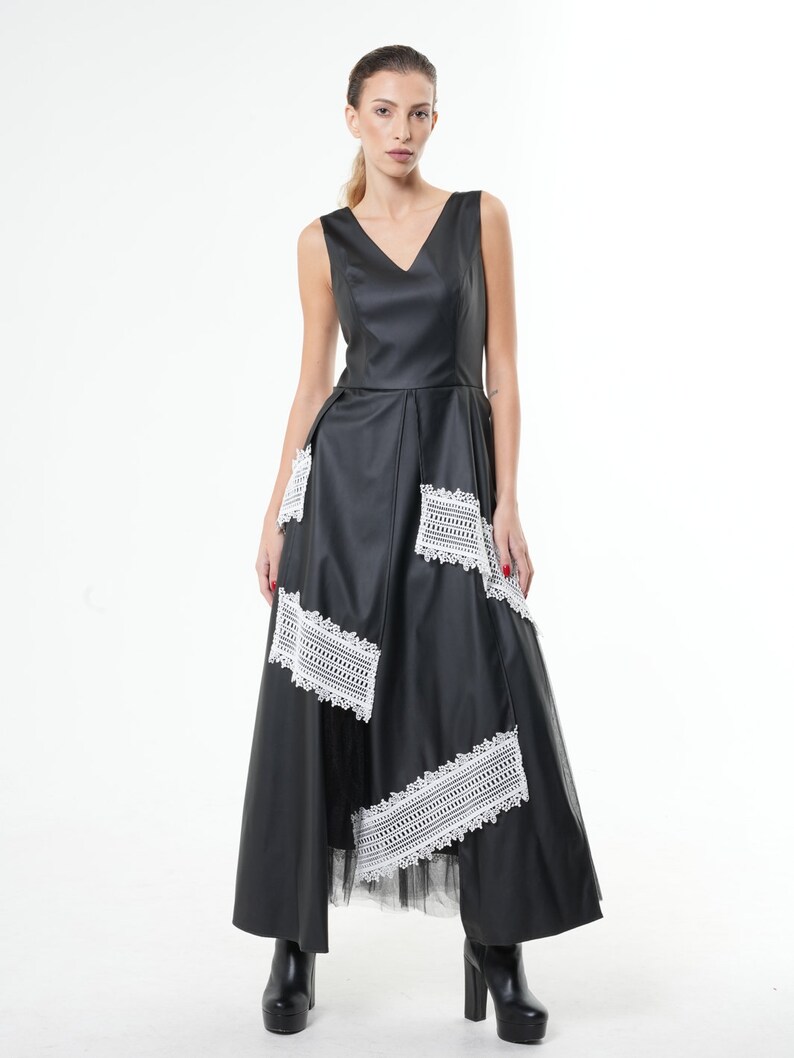 May include: A black maxi dress with a V-neckline and white lace detailing. The dress has a fitted bodice and a flowing skirt.