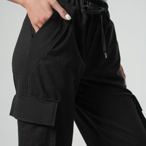 May include: Black cargo pants with a drawstring waist and side pockets. The pants have a relaxed fit and are made of a soft, comfortable fabric.