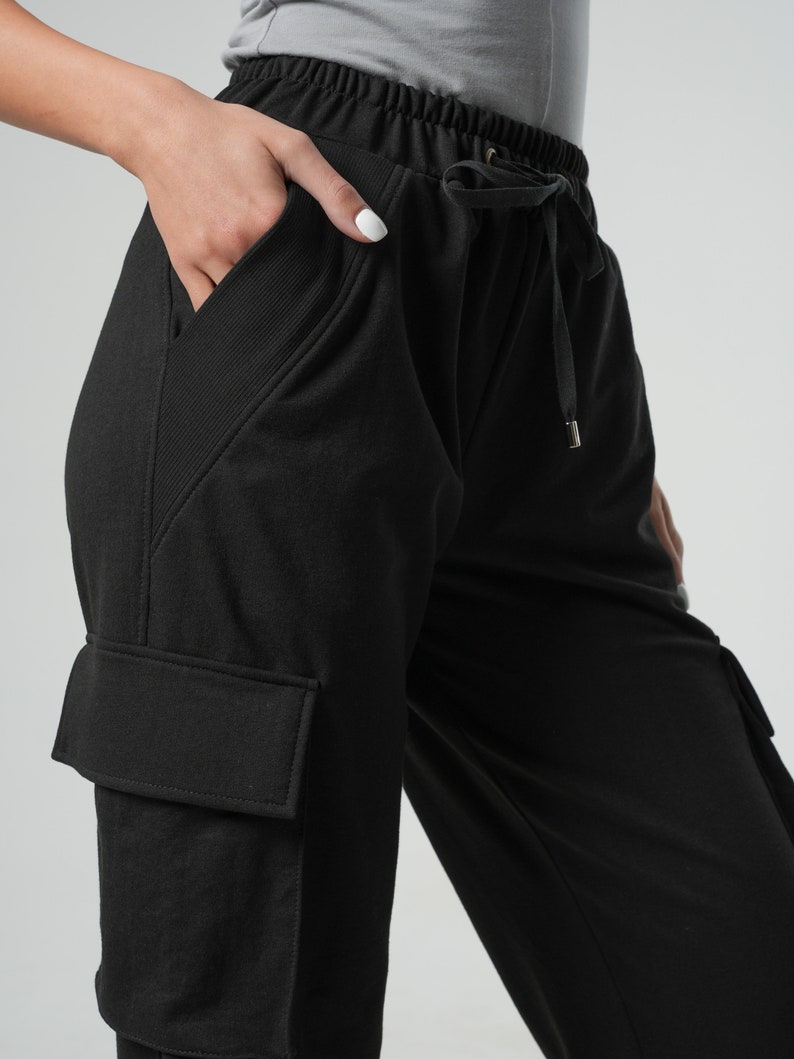 May include: Black cargo pants with a drawstring waist and side pockets. The pants have a relaxed fit and are made of a soft, comfortable fabric.