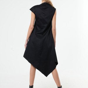 K&ouml;nnte beinhalten: Ein schwarzes &auml;rmelloses Kleid mit hohem Ausschnitt und asymmetrischem Saum. Das Kleid ist aus einem weichen, flie&szlig;enden Stoff.