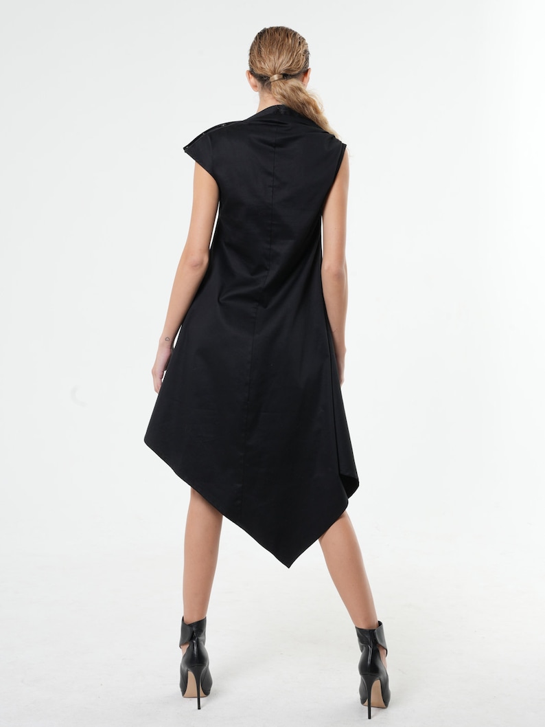 K&ouml;nnte beinhalten: Ein schwarzes &auml;rmelloses Kleid mit hohem Ausschnitt und asymmetrischem Saum. Das Kleid ist aus einem weichen, flie&szlig;enden Stoff.