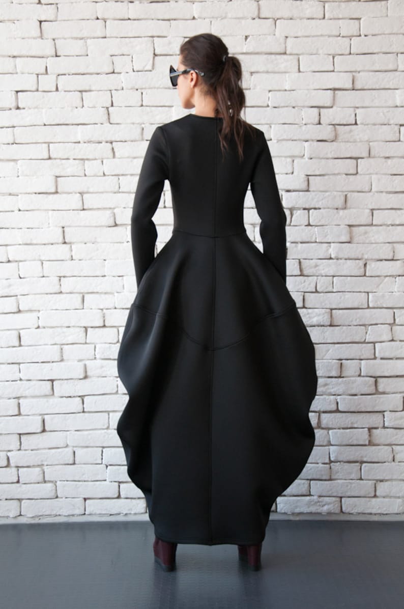 Pu&ograve; includere: Un abito nero a maniche lunghe con una gonna voluminosa e un corpetto aderente. L'abito &egrave; realizzato in un tessuto spesso ed elastico e ha un design semplice ed elegante.