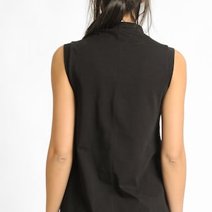 May include: A black sleeveless mock neck shirt.