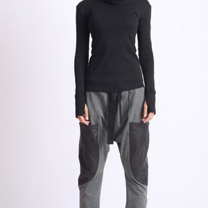 May include: A black turtleneck shirt with long sleeves and a gray pair of pants with black accents. The pants have a loose fit and a drawstring waist.