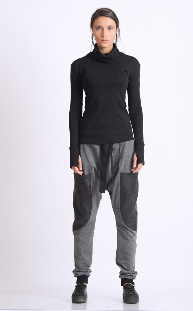 May include: A black turtleneck shirt with long sleeves and a gray pair of pants with black accents. The pants have a loose fit and a drawstring waist.