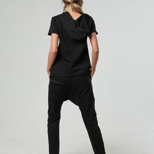May include: A black short-sleeved hooded top with a relaxed fit and black pants.