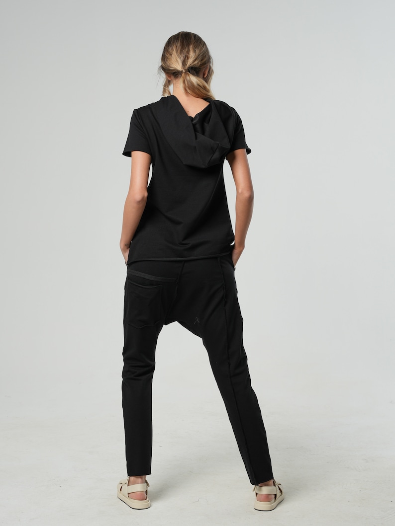May include: A black short-sleeved hooded top with a relaxed fit and black pants.