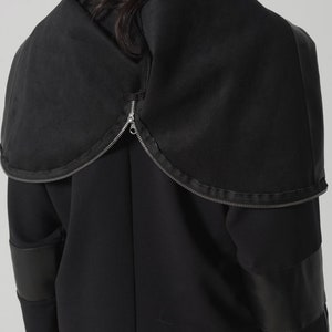 以下が含まれることがあります： フロントにジッパーが付いた黒いフード付きジャケット。袖に革のアクセントが付いている。