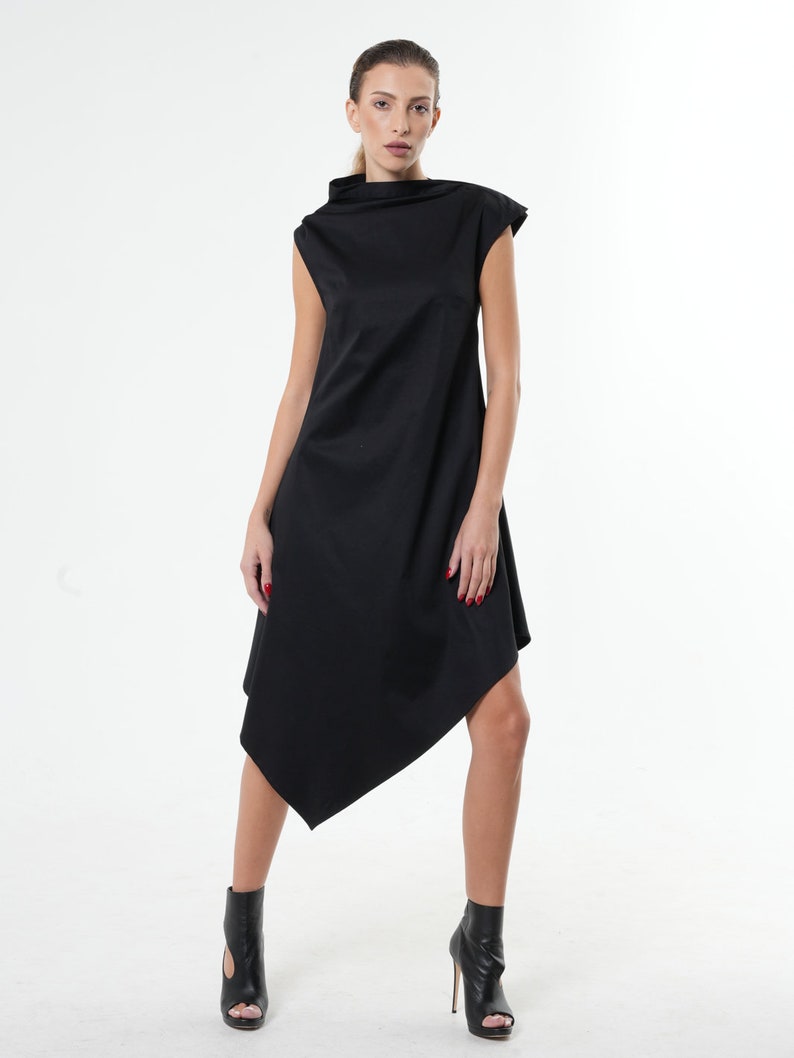 K&ouml;nnte beinhalten: Ein schwarzes &auml;rmelloses Kleid mit hohem Ausschnitt und asymmetrischem Saum. Das Kleid ist aus einem weichen, flie&szlig;enden Stoff gefertigt.