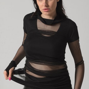 May include: A black long-sleeved shirt with a sheer mesh overlay. The shirt has a mock neck and a fitted silhouette.