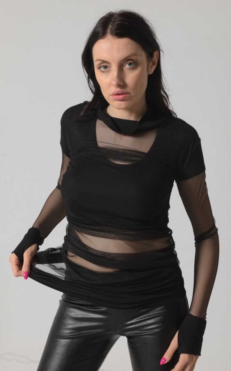 May include: A black long-sleeved shirt with a sheer mesh overlay. The shirt has a mock neck and a fitted silhouette.