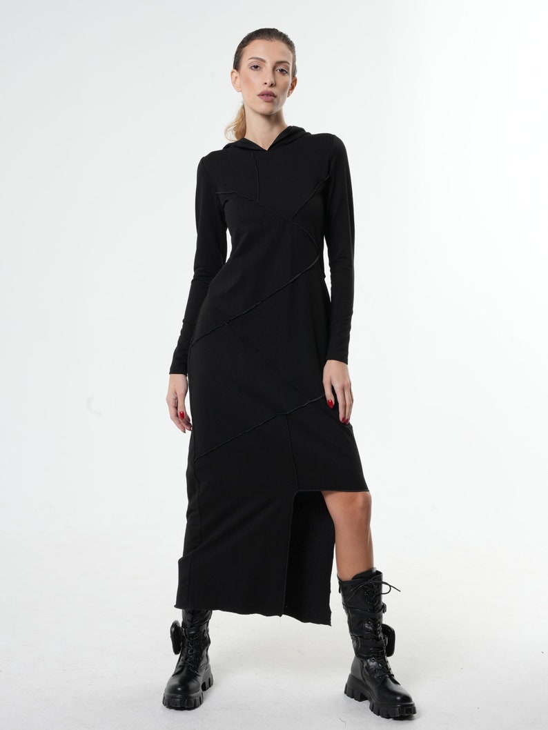 May include: A black long-sleeved hooded dress with a side slit and asymmetrical seams. The dress is made of a soft, stretchy fabric.