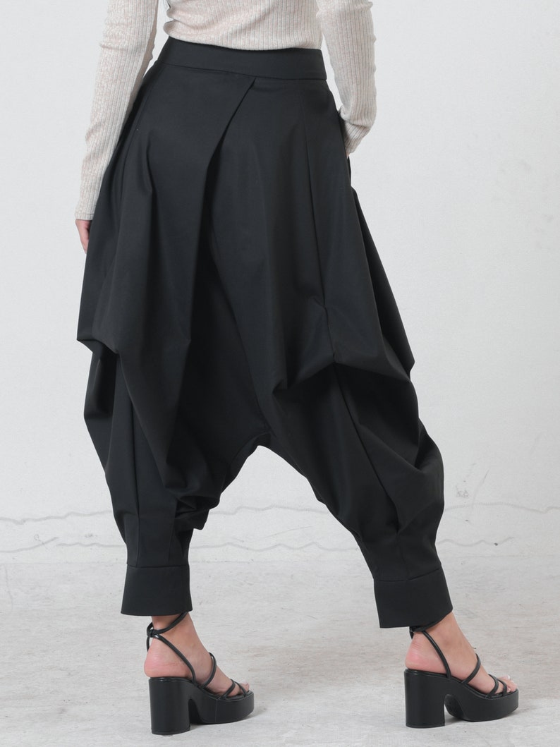 May include: Black, wide-leg pants with a unique, gathered design. The pants have a high waist and a loose, flowing fit.