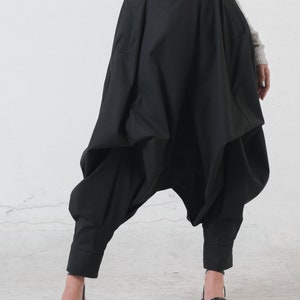 May include: Black, loose-fitting pants with a high waist and a unique, gathered design. The pants have a wide leg and a cropped length.