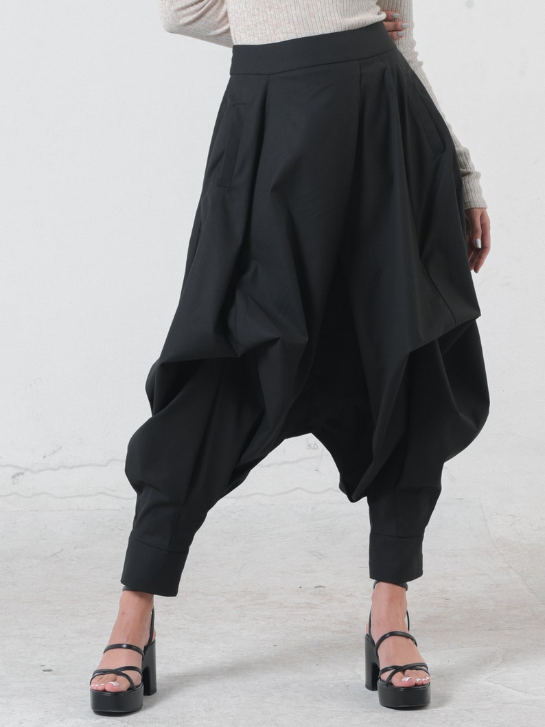 May include: Black, loose-fitting pants with a high waist and a unique, gathered design. The pants have a wide leg and a cropped length.