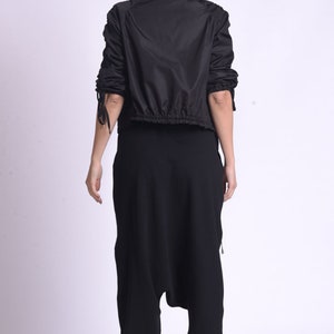 May include: A black hooded jacket with a drawstring waist and long sleeves. The jacket has a zipper closure and is made of a lightweight material.