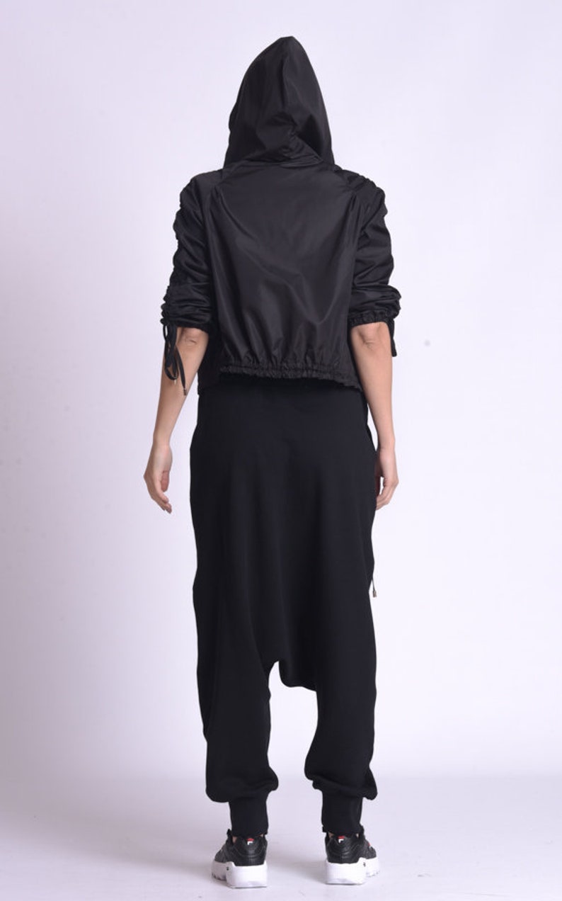 May include: A black hooded jacket with a drawstring waist and long sleeves. The jacket has a zipper closure and is made of a lightweight material.