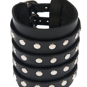 May include: Black leather cuff bracelet with silver studs and a double buckle closure.