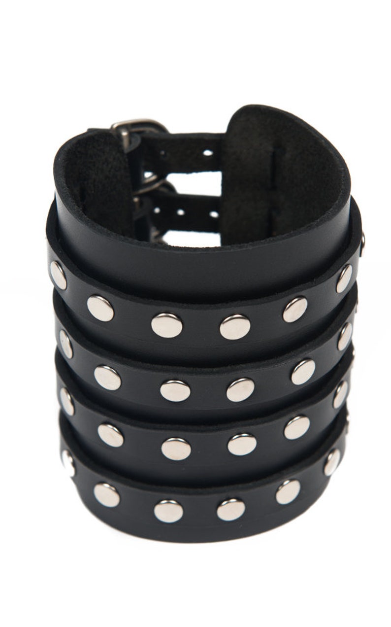 May include: Black leather cuff bracelet with silver studs and a double buckle closure.