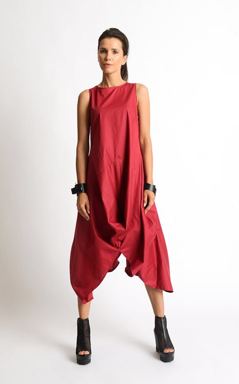 Peut inclure: Une combinaison rouge sans manches &agrave; la coupe ample et fluide. La combinaison a une jambe large et une taille fronc&eacute;e. Le mannequin porte des bottines noires &agrave; la cheville.