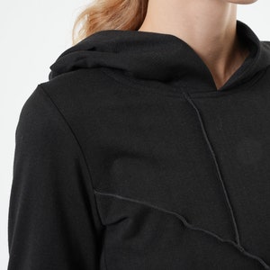 May include: Black long-sleeved hooded sweatshirt with a contrasting stitch detail on the front.